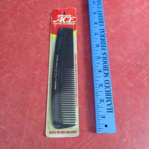May include: A black Ace hard rubber comb in its original packaging, with a red and yellow header. A blue ruler is next to the comb. The comb is labeled "Gentle on Hair and Scalp."