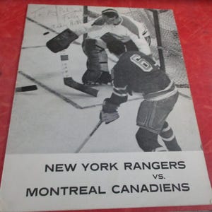 May include: Black and white vintage hockey program featuring a game between the New York Rangers and the Montreal Canadiens. The image shows players on the ice, with the text "NEW YORK RANGERS vs. MONTREAL CANADIENS" at the bottom.
