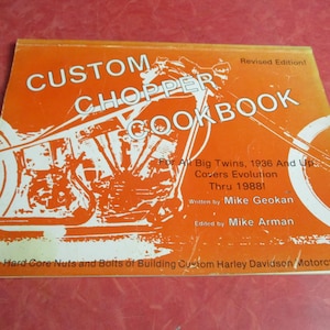 May include: An orange book titled "Custom Chopper Cookbook" with white text and a motorcycle graphic. The book covers Harley Davidson motorcycles from 1936 to 1988. Written by Mike Geokan and edited by Mike Arman.
