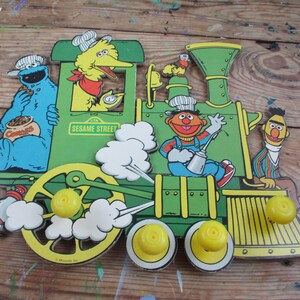 Sesame Street wall hanging with 4 pegs Green and Yellow Train with Bert and Ernie, Cookie Monster, G Big Bird Jim Henson Muppets 17" x 15"