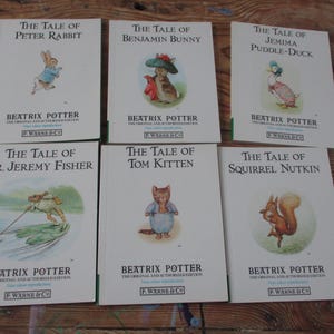 Op de afbeelding: Een collectie van zes Beatrix Potter boeken met witte covers, voorzien van illustraties van Peter Rabbit, Benjamin Bunny, Jemima Puddle-Duck, Mr. Jeremy Fisher, Tom Kitten en Squirrel Nutkin, allen uitgegeven door F. Warne & Co.
