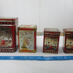 Puede incluir: Cuatro latas de almacenamiento de metal vintage con detalles en rojo y dorado. Cada lata presenta un diseño de inspiración asiática con figuras y paisajes. Las latas varían en tamaño, siendo la más grande rectangular y la más pequeña cuadrada.