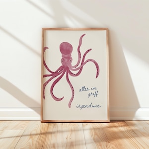 May include: A framed art print with a purple octopus watercolour illustration on a cream background. The octopus has multiple tentacles. The print includes the German text "alles im griff irgendwie."