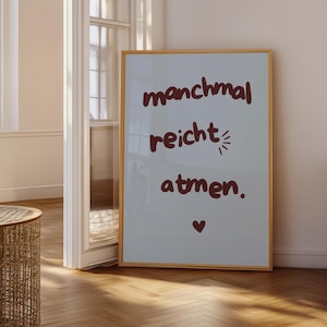 Op de afbeelding: Een ingelijste print met de Duitse tekst "manchmal reicht atmen" in bordeauxrood. De print bevat een klein hartsymbool. De lijst is licht van kleur en de achtergrond is lichtgrijs.