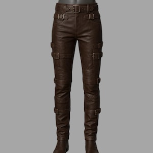 May include: Brown leather pants with multiple buckle details. The pants have a fitted design with several straps and buckles running down the legs and around the waist. The pants are made of a smooth, dark brown leather material.