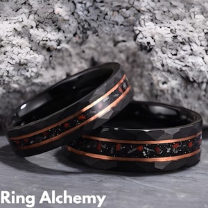 May include: Two black tungsten carbide rings with a hammered finish and a copper inlay. The inlay features red and black flecks.