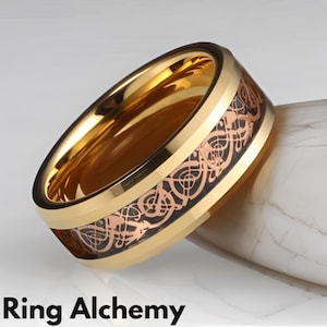 May include: A gold ring featuring a black and rose gold intricate design. The ring is crafted from tungsten carbide and has a polished finish.