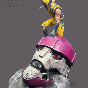 May include: A detailed figurine of Wolverine in a dynamic pose, wearing a yellow and blue costume, standing atop a damaged Sentinel head. The Sentinel head is primarily grey with a pink helmet and red eyes. The figurine is set against a grey background.