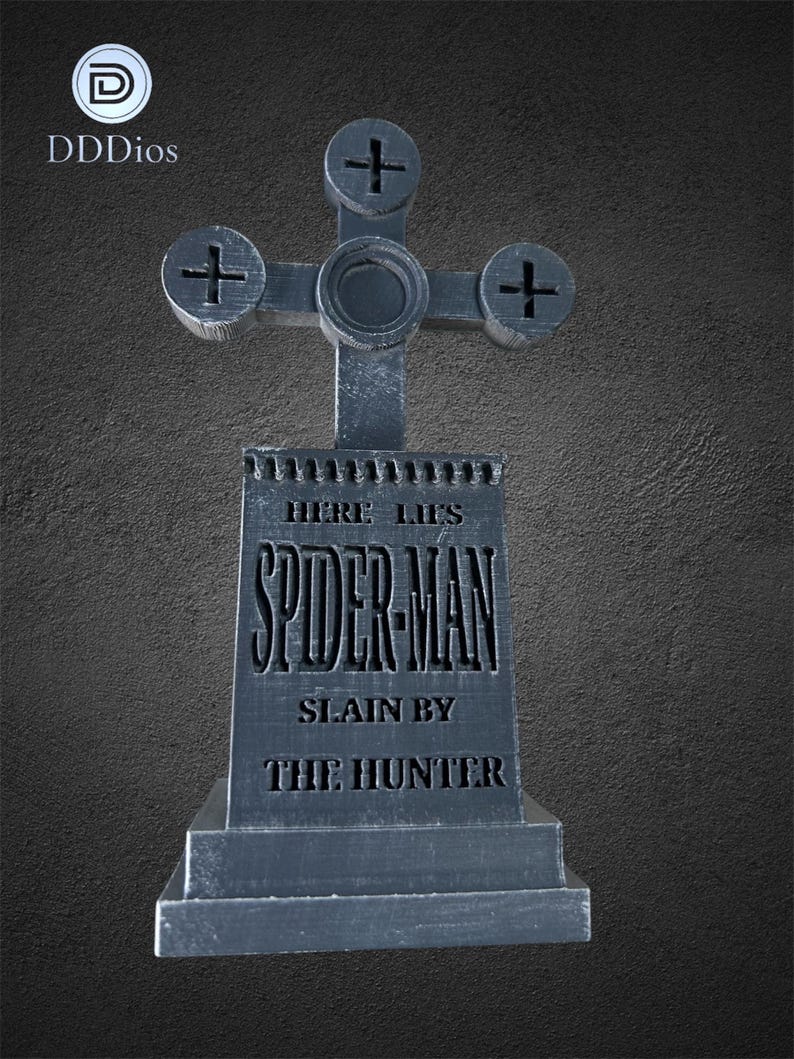May include: A gray, stylized tombstone with a cross-shaped top. The text "HERE LIES SPIDER-MAN SLAIN BY THE HUNTER" is engraved on the front. The tombstone has a weathered appearance, suggesting it is made of stone.