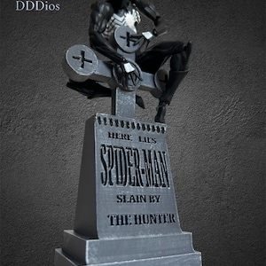 May include: A black and white Spider-Man action figure sits atop a gray tombstone. The tombstone reads "Here Lies Spider-Man, Slain by The Hunter." The figure is detailed with a white spider emblem on the chest.