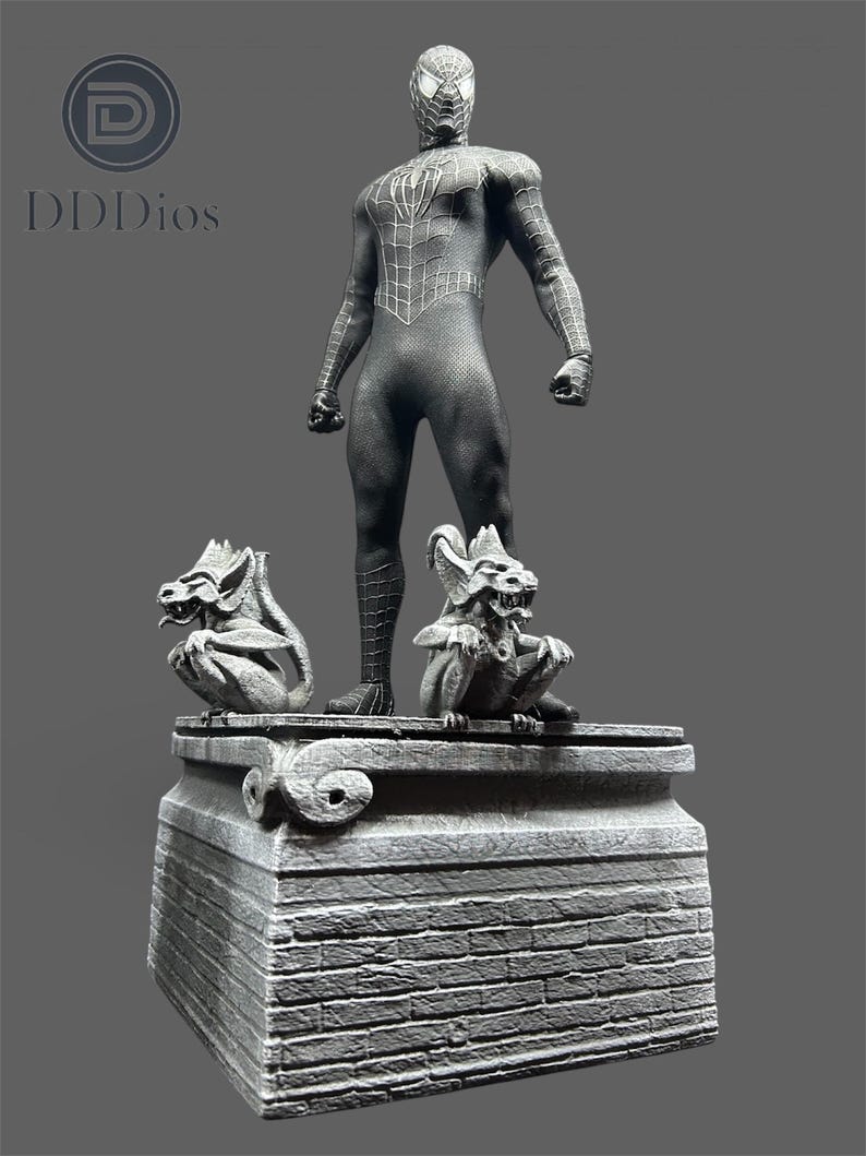 Pode incluir: Uma est&aacute;tua detalhada do Homem-Aranha em um traje preto, em cima de uma plataforma de pedra com duas g&aacute;rgulas. A est&aacute;tua &eacute; cinza e preta, com detalhes intrincados de teia. A plataforma tem uma textura semelhante &agrave; de tijolos.
