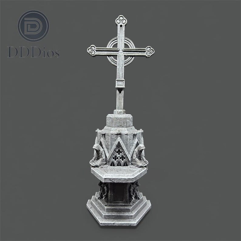 May include: A gray, gothic-style cross statue with intricate detailing. The cross features a circular design at the intersection and sits atop a multi-tiered base with sculpted figures. The base has the text "DDDios".