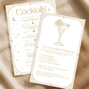 May include: Two cocktail recipe cards with gold text and decorative borders. One card lists cocktail names like "The Fool's Leap" and "The Magician's." The other card features "The Moonlight Margarita" recipe, including ingredients and instructions.