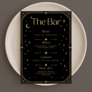 May include: A black bar menu with gold celestial accents, including stars and crescent moons. The menu lists beer, wine, liquor, and non-alcoholic beverages. The text "The Bar" is at the top.