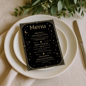 Puede incluir: Una tarjeta de menú negra con texto dorado y diseños celestiales, incluyendo estrellas y lunas crecientes. El menú está sobre un plato blanco, con un cuchillo a la derecha. El menú enumera entrantes, platos principales y postres. La tarjeta tiene un marco decorativo.