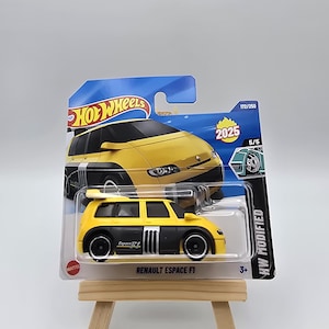 Może przedstawiać: Żółto-czarny samochodzik Renault Espace F1 na niebiesko-białej karcie Hot Wheels. Samochód ma czarne koła i napis "Espace F1" z boku. Karta zawiera napisy "HW Modified" i "2025".