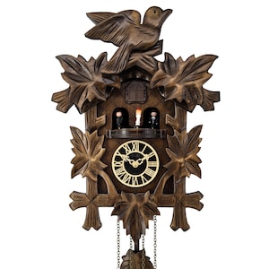 May include: A wooden cuckoo clock with a bird on top and leaf-shaped accents. The clock face has Roman numerals, and two small figures are visible inside. The clock has decorative pinecone weights and chains.