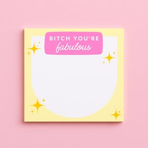 May include: A yellow sticky note with a white interior and a pink rectangular banner that reads "BITCH YOU'RE fabulous" in white script. The note has four yellow starbursts in each corner. The background is pink.