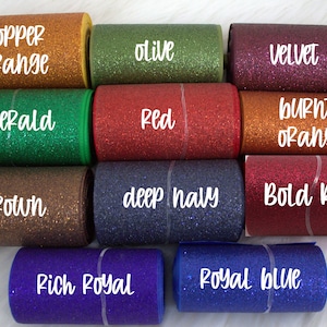 May include: A collection of ten rolls of glitter ribbon in various colors, including copper orange, olive, velvet, emerald, red, burnt orange, brown, deep navy, bold red, rich royal, and royal blue.