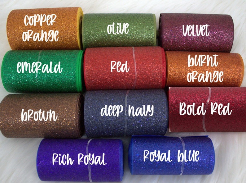 May include: A collection of ten rolls of glitter ribbon in various colors, including copper orange, olive, velvet, emerald, red, burnt orange, brown, deep navy, bold red, rich royal, and royal blue.