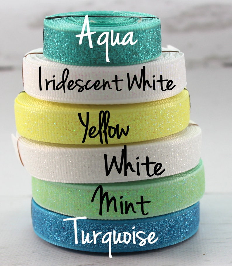 May include: A stack of six different colored glitter ribbon rolls. The colors are turquoise, mint, white, yellow, iridescent white, and aqua.