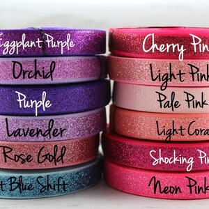 May include: A stack of 12 rolls of glitter ribbon in various shades of purple, pink, and coral. The ribbon is labeled with the following colors: Eggplant Purple, Orchid, Purple, Lavender, Rose Gold, Light Blue Shift, Cherry Pink, Light Pink, Pale Pink, Light Coral, Shocking Pink, and Neon Pink.