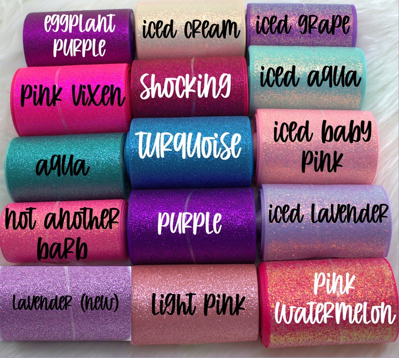 May include: A collection of 10 rolls of glitter ribbon in various colors, including pink, purple, aqua, and lavender. The ribbon is labeled with names like "Pink Vixen", "Shocking Turquoise", "Iced Grape", and "Light Pink".