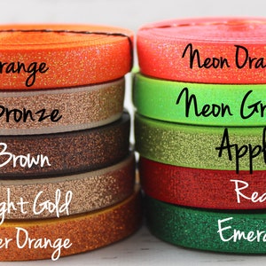 May include: A close-up of ten spools of glitter elastic ribbon in various colors, including orange, bronze, brown, light gold, copper orange, neon orange, neon green, apple, red, and emerald.