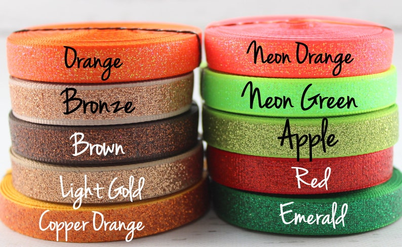 May include: A close-up of ten spools of glitter elastic ribbon in various colors, including orange, bronze, brown, light gold, copper orange, neon orange, neon green, apple, red, and emerald.