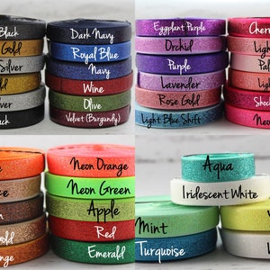 May include: Assortment of colorful glitter ribbon rolls in various colors, including black, gold, silver, navy, blue, purple, pink, orange, green, red, white, and yellow. The ribbon rolls are arranged in rows and labeled with their respective colors.