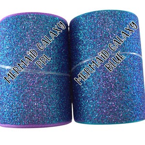 May include: Two rolls of glitter ribbon, one purple and one teal, with the text "Mermaid Galaxy" and the color name printed on each roll.