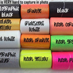 May include: A collection of 12 different colors of glitter ribbon, including holographic black, orange, golden yellow, iridescent white, iced white, holographic silver, neon orange, neon green, neon yellow, neon pink, and neon coral.