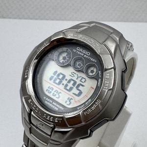 May include: A metallic silver Casio G-Shock digital watch with a link bracelet. The watch face displays the time 18:05, the text SYD, and features including 10 YEAR BATTERY, e-DATA MEMORY, and WR200M. The bezel is engraved with G-SHOCK and SHOCK RESIST.