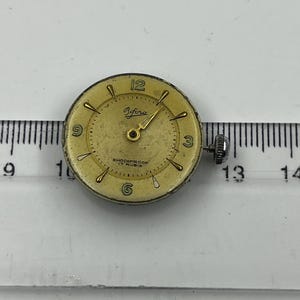 以下が含まれることがあります： 金色の文字盤、黒い数字と針を備えた、ヴィンテージのBiforaの時計の文字盤。 時計の文字盤には「Bifora」と「Shockproof 17 Rubis」の文字があります。 時計の文字盤の直径は約2.5cmです。