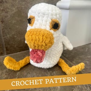 May include: Crochet pattern for a white amigurumi goose with a yellow beak and pink tongue. The goose has brown eyes and yellow feet.