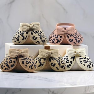May include: Four leopard print sun hats with bows. The hats are in different shades of beige and cream.