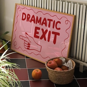 May include: A pink framed sign with the words "DRAMATIC EXIT" in red, with a pointing hand graphic. The sign rests on a red and black tiled floor, near a basket of apples and potted plants.