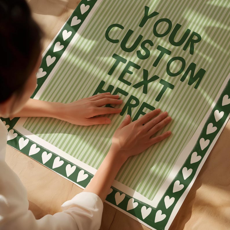 Pu&ograve; includere: Un poster a righe verdi e bianche con la scritta "YOUR CUSTOM TEXT HERE" in verde scuro. Il poster ha un bordo di cuori bianchi su sfondo verde.