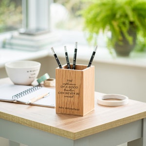 May include: A wooden pencil holder with the quote "The influence of a good teacher can never be erased" engraved on the front. The holder is personalized with the name "Mrs. Whitefield".