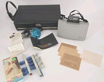 Kit de cámara Polaroid 210 Land con estuche, bombillas de flash, manual y accesorios vintage.