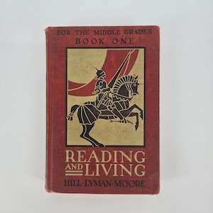 Könnte beinhalten: Ein Vintage-Buch mit dem Titel "Reading and Living" für die Mittelstufen. Das Cover ist tiefrot mit goldenen und schwarzen Illustrationen eines Ritters zu Pferd. Der Text "Book One" steht oben.