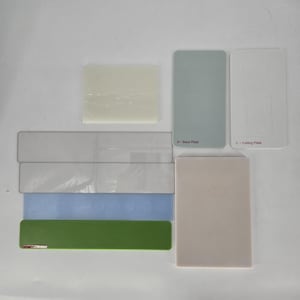 May include: A collection of rectangular craft plates including a white translucent block, a grey plate labelled A - Base Plate, a white plate labelled C - Cutting Plate, two clear acrylic strips, a blue strip, a green strip, and a large beige plate.