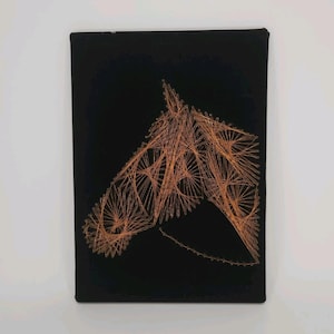 May include: A rectangular black wall art piece featuring a horse head silhouette created with copper-colored string art. The design is formed by thin threads stretched between small nails, outlining the equine profile against the dark background.