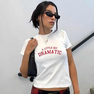 May include: White t-shirt with a pink graphic that says "A little bit dramatic".