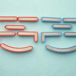 May include: A collection of red and blue signs, each bearing the word "Deployment". The signs are in arrow shapes, some straight, some curved, and some L-shaped, set against a pale blue backdrop.