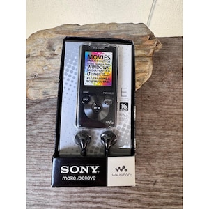 May include: A black Sony NWZ-E385 Walkman MP3 player with 16 GB of storage, displayed in its original packaging. The packaging includes the player, earbuds, and text that reads "MOVIES, MUSIC & PHOTOS, WINDOWS, iTunes, CLEAR SOUND & POWERFUL BASS."