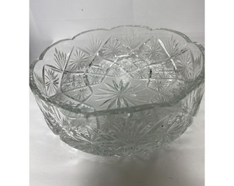 May include: A clear glass bowl with a cut-glass design. The bowl has a scalloped edge and a starburst pattern.