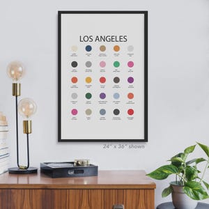 May include: A framed art print with the text "LOS ANGELES" at the top. The print features a grid of colorful circles, each labeled with a location or landmark. The frame is black, and the print size is 24 x 36 inches.