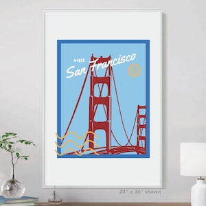 May include: Framed art print featuring the Golden Gate Bridge in San Francisco. The artwork has a retro travel poster style with a red bridge against a blue sky. The text "Visit San Francisco" is displayed in a vintage font.