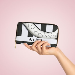 May include: A rectangular wallet featuring a black and white striped pattern with a large, curved, white, cracked horn-like graphic across the top. The word KEITH is printed in black, stylised, handwritten-style letters on the white section.
